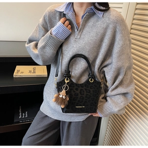 Détail du sac à main léopard noir avec poignée nouée et breloque peluche