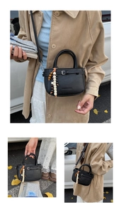 Detail of black leather crossbody bag with wooden bead charm and elegant shoulder strap
