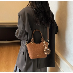 Close-up of a brown leopard print bucket bag featuring a soft suede texture and plush charm