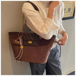 Close-up of brown suede tote bag with quilted leather flap and gold chain strap