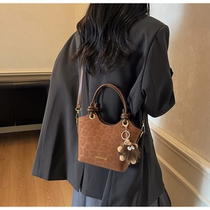 Detail of leopard print bucket bag with gold logo and plush bear charm on model