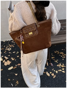 Brown suede tote bag detail featuring gold chain strap and quilted pocket with turn-lock