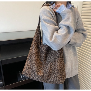 Detailed close-up of large leopard print hobo bag worn by a model in a modern interior