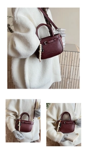 Detail view of burgundy leather handbag with beaded charm and silver buckle strap