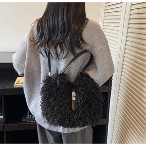 Detail of black faux fur shoulder bag with silver metal swivel lock on gray sweater