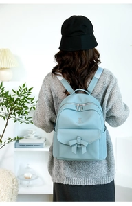 Dettaglio dello zaino celeste con fiocco in pelle PU martellata e logo in metallo