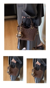 Détail d'un sac seau léopard marron avec pendentif monstre en peluche et bandoulière chic