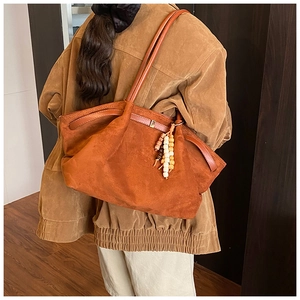 Tragebild der großen orangefarbenen Wildleder-Tasche mit dekorativem Holzperlen-Anhänger