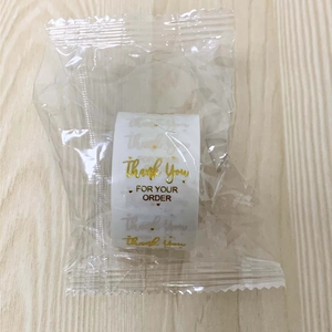 Detail of 1-inch thank you sticker rolls with gold foil lettering for packaging