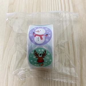 Detailed view of Christmas sticker roll with snowman and elk on wooden background
