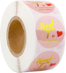 Macro view of pink adhesive thank you stickers roll with gold foil lettering