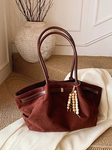 Dunkelbraune Retro-Tasche aus Wildlederimitat mit Perlenanhänger auf Textur