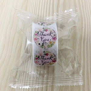 Macro shot of roll-packed thank you labels with floral patterns and cursive typography