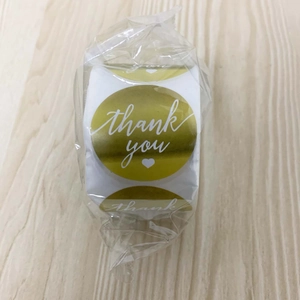 Macro detail of round gold 'Thank You' roll stickers packaged in a clear plastic bag