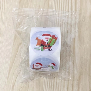 Detail view of 3.8cm Christmas stickers roll with Santa and snowman on wood background