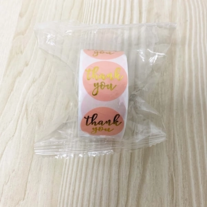 Detail view of pink round Thank You stickers in a 1-inch roll with gold lettering
