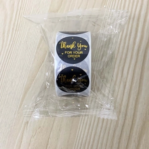 Detail of round black thank you stickers with gold foil text for gift packaging