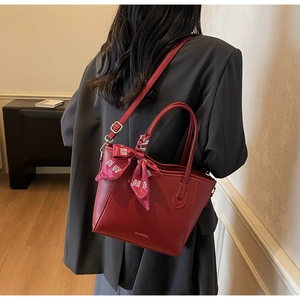 Dettaglio borsa tote rossa con foulard di seta festivo e tracolla in pelle regolabile