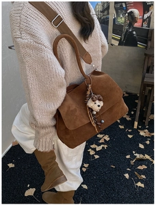 Dettaglio borsa tote opaca color terra con tracolla larga e ciondolo a orsetto peluche