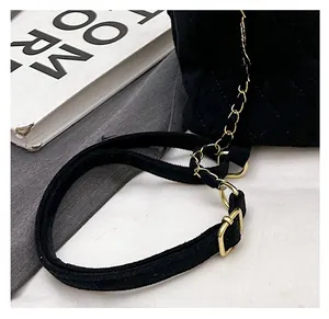 Detail of adjustable gold chain strap and suede quilted texture on mini black backpack