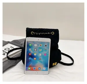 Quilted black suede mini backpack with golden chain compared to tablet for size scale