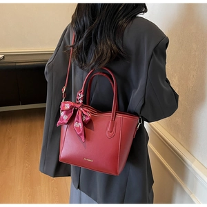 Borsa tote bordeaux con sciarpa decorativa indossata a spalla con blazer grigio
