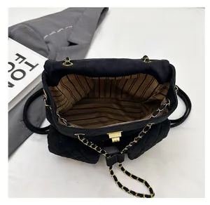 Detail of mini quilted backpack with striped lining and gold chain strap