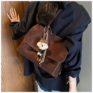 Dettaglio borsa a tracolla vintage in pelle scamosciata marrone con ciondoli e peluche