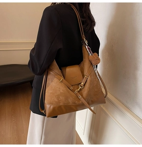 Detail of caramel tote bag with matte leather stitching and a plush bear pendant