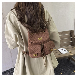 Close-up of brown quilted suede mini backpack with gold chain straps and metal twist locks