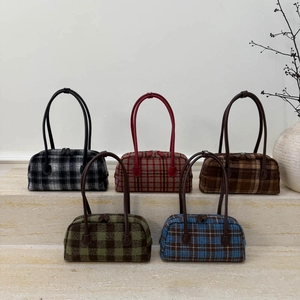 Détails de cinq sacs Boston à carreaux aux couleurs automnales sur des marches en pierre