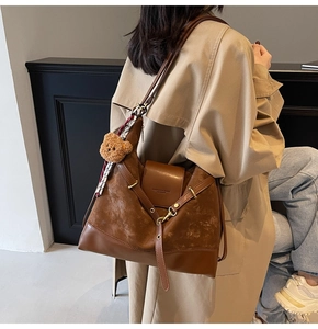 Close-up of brown suede patchwork tote bag with cute bear charm and silk scarf detail