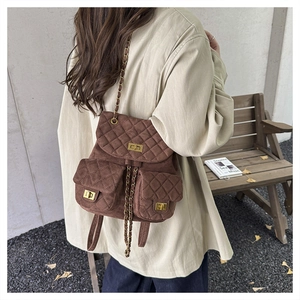 Detail of dark brown quilted suede backpack with gold hardware and chain drawstring
