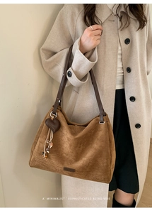 Close-up of vintage brown suede tote bag with heart charm and tassel detail