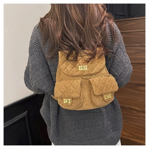 Detail of quilted brown suede backpack with gold chain straps and turn-lock closures