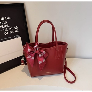 Dettaglio della borsa tote bordeaux in pelle con foulard in seta e logo dorato su bianco