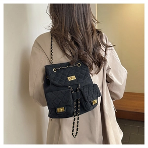 Detail of black quilted velvet mini backpack with gold chain straps and metal twist locks