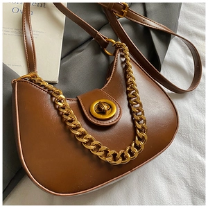 Détail d'un sac demi-lune marron avec chaîne dorée et fermeture à loquet métallique