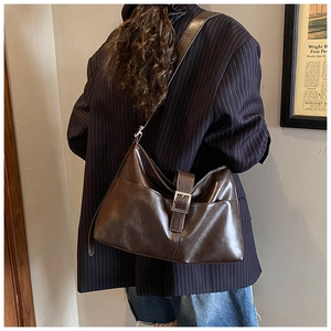 Detail of vintage brown tote bag with leather strap and silver metal buckle on model