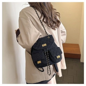 Macro detail of black quilted suede backpack with golden chain strap on a model