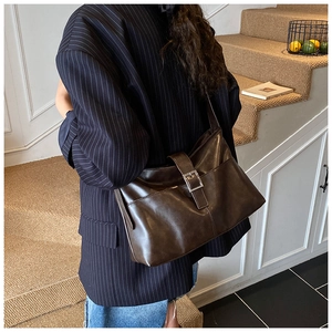 Detail of dark brown vintage faux leather shoulder bag with metallic buckle on strap