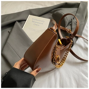 Détail d'un sac demi-lune marron foncé avec chaîne dorée et fermoir pivotant