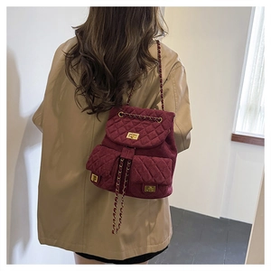 Detail of burgundy quilted velvet mini backpack with gold chain straps and turn-lock