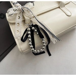 Détail du porte-clés à billes argentées avec nœud en velours et dentelle sur le sac