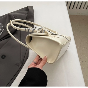 Détail du sac bandoulière en cuir blanc cassé avec un élégant foulard à carreaux sur l'anse