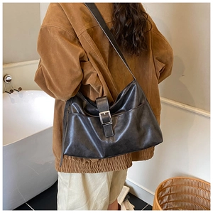 Detail of a large black hobo shoulder bag with a silver metal buckle and adjustable strap