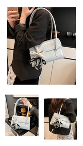 Detail view of the light blue leather underarm bag with decorative ribbon and pearl chain