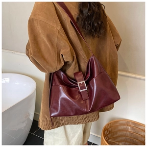 Detail of burgundy large tote bag with silver square buckle worn by a model