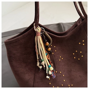 Nahaufnahme braune Wildleder-Tote Bag mit Vintage-Nieten und bunten Quastenanhängern