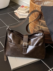 Vintage dark brown crossbody shoulder bag with silver buckle on black and white tile background